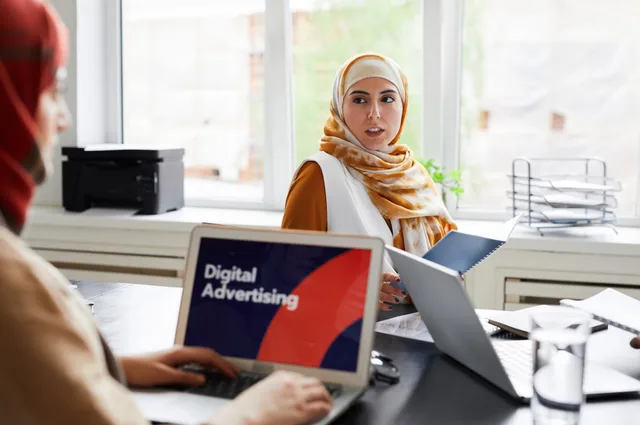 Two women in hijabs discuss digital advertising in an office setting. Reklamregler i Sverige: lagar, branschregler och tillsyn